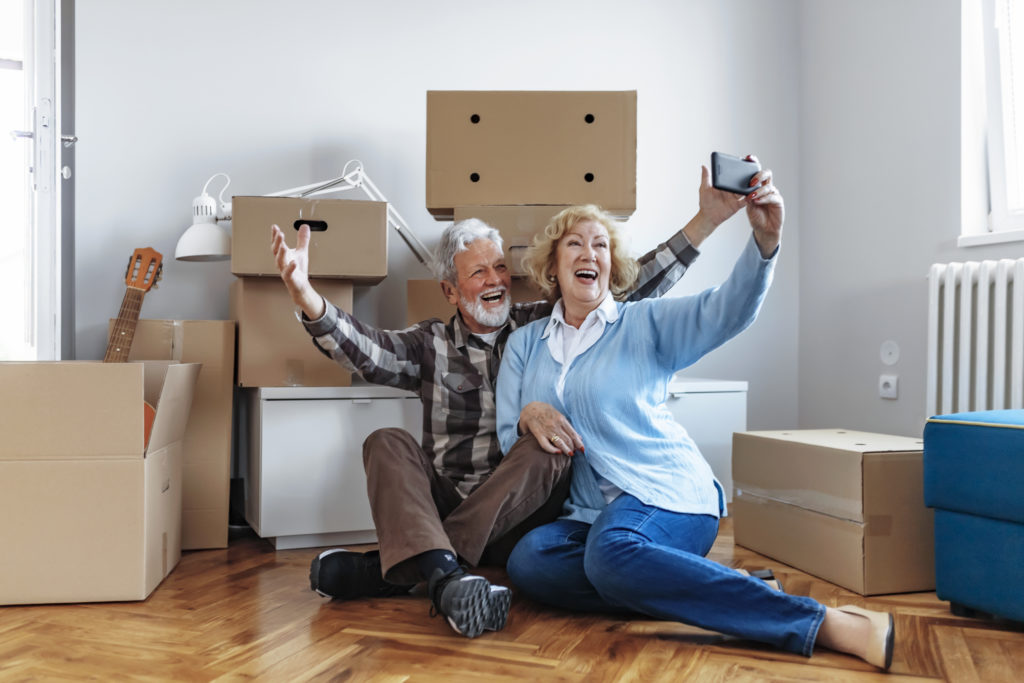 Happy Senior couple poses for selfie while moving in.