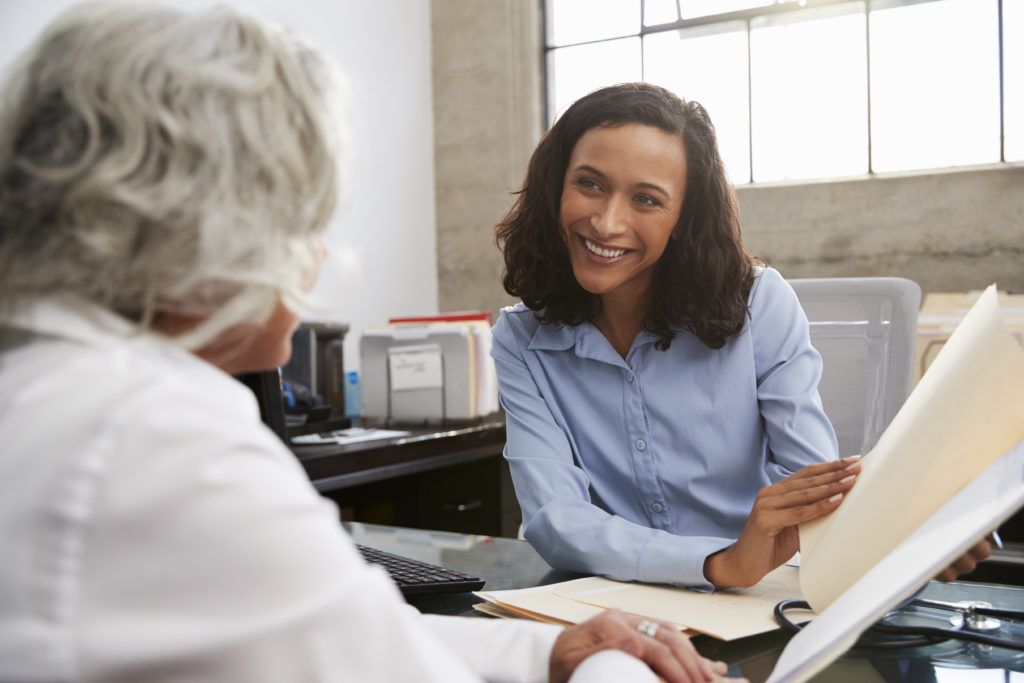 Excited senior living executive reviewing new apartment contract with retired woman. Reviewing New Contract Prior to Signing